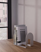 White metal bookend holding books on a wooden shelf