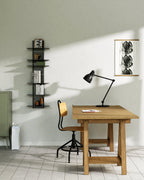 Black modular wall shelf with books and objects beside desk