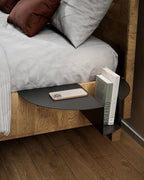 Black nightstand attached to wooden bed with phone and books