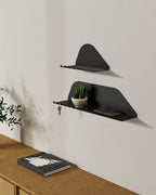 Black wall shelves with hooks holding keys above wooden console