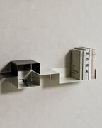 Black and white modular wall shelves with books and small objects