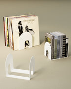White metal bookend shown with books and vinyl records on light background