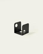 Black metal bookend with U-shape and circular cutouts on light background