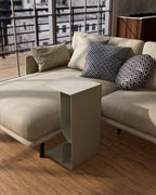 white metal side table with book rack beside beige sofa