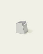 White metal pen holder with folded front edge on light background