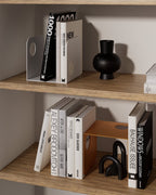 White and terracotta metal bookends holding books on wooden shelves