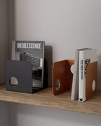 Black and terracotta metal bookends holding books on wooden shelf