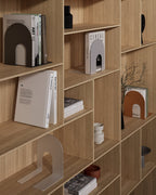 Metal bookends in black, white, and orange displayed across wooden shelves