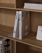 White metal bookend supporting books on a wooden shelf