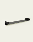 Black metal wall shelf on light background