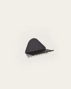 Black metal wall shelf with hooks underneath on light background