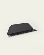 Black metal wall shelf with hooks underneath on light background