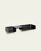 Black modular metal wall shelf on light background