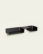 Black modular metal wall shelf on light background