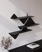 black modular wall shelves in staggered arrangement above console table