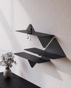 black modular wall shelves in staggered arrangement above console table