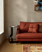 Black metal side table with built-in book rack beside rust sofa