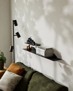 Two black floating metal wall shelves with books and small objects