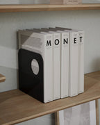 Black metal bookend holding books on a wooden shelf
