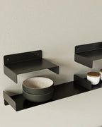 Black metal wall shelves with bowls and jars in kitche