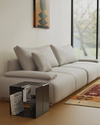 Black modular metal side table with books beside white sofa