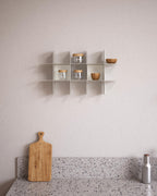 White modular wall shelf with jars and bowls above kitchen counter