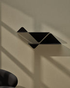 Black modular wall shelf mounted on wall in stepped configuration