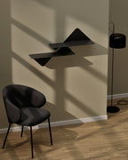 Grouped black modular wall shelves mounted on wall beside chair and floor lamp
