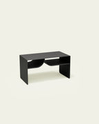 Black metal coffee table with built-in book rack on light background