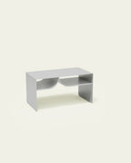 White metal coffee table with built-in book rack on light background