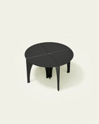 Black modular steel coffee table arranged as a round table on light background
